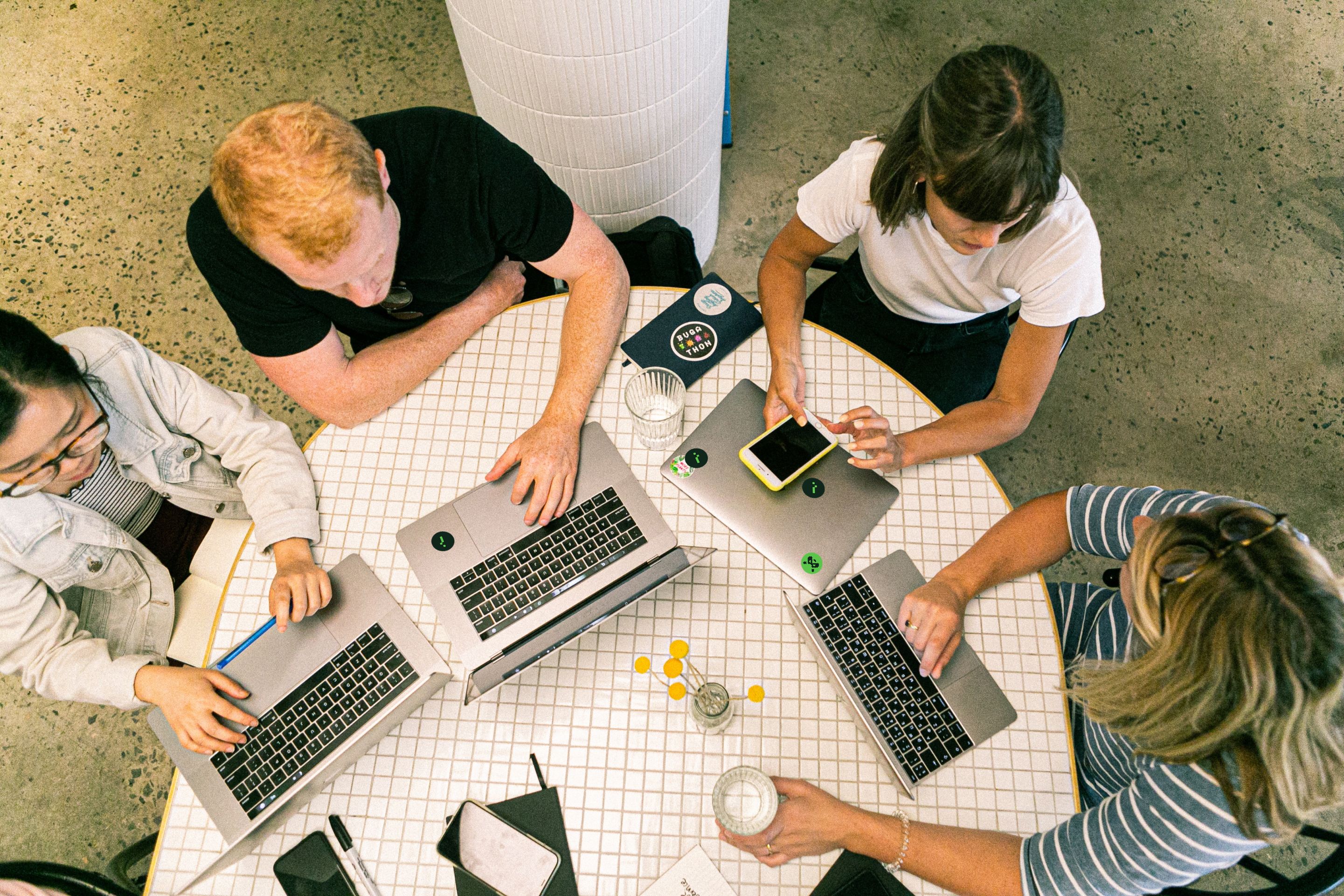 Team members sitting on a round table with laptops