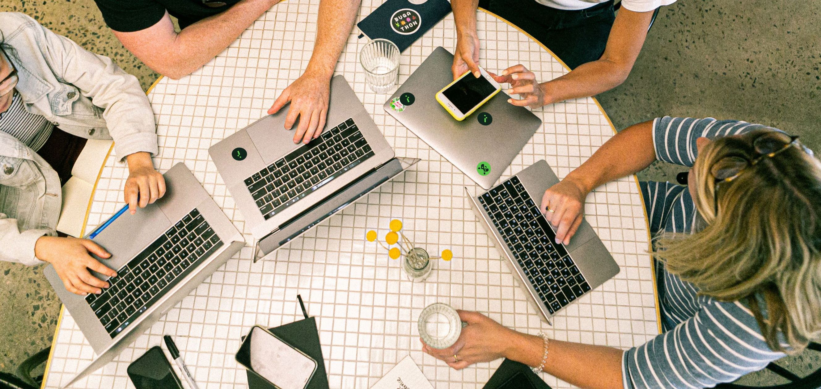 Team members sitting on a round table with laptops